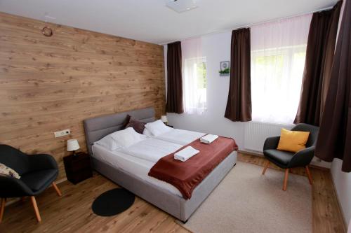 a bedroom with a bed and two chairs at Villa Terrasse in Eger