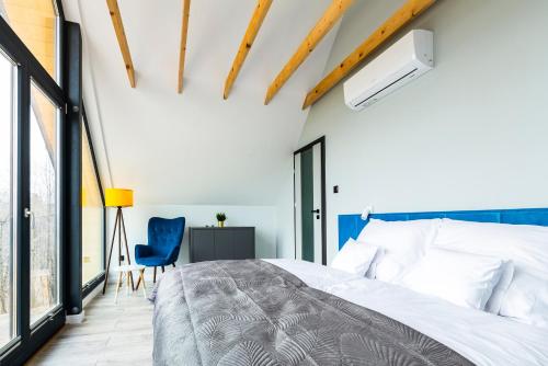 a bedroom with a bed and a blue chair at Sośnie Górne Resort & Spa in Grybów