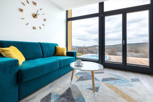 a living room with a blue couch and a table at Sośnie Górne Resort & Spa in Grybów