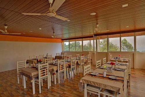 a dining room with tables and chairs and windows at Iceberg Hill View Resort Munnar in Munnar