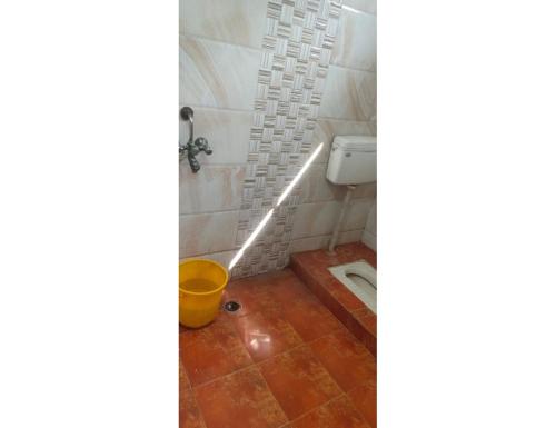 a bathroom with a toilet and a yellow bucket at Hotel Prem Sagar, Agra Cantt in Agra