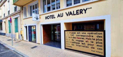 un magasin avec un panneau sur le côté d'un bâtiment dans l'établissement Hôtel Au Valéry, à Sète