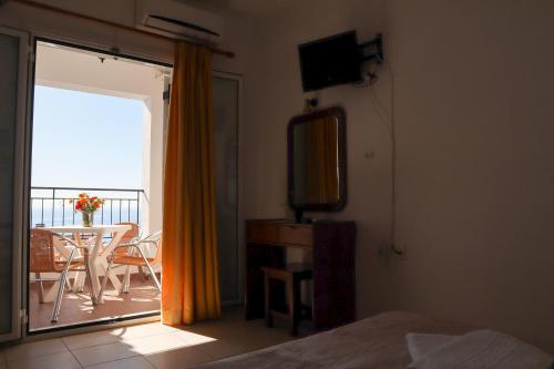 a bedroom with a bed and a balcony with a table at Spyridoula in Lourdhata