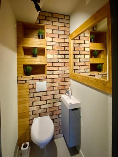 a bathroom with a toilet and a brick wall at Yose Apartment - 160 m2 na wyłączność in Poznań