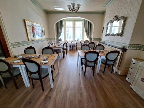 a restaurant with wooden tables and chairs in a room at Lily Hotel in Blackpool
