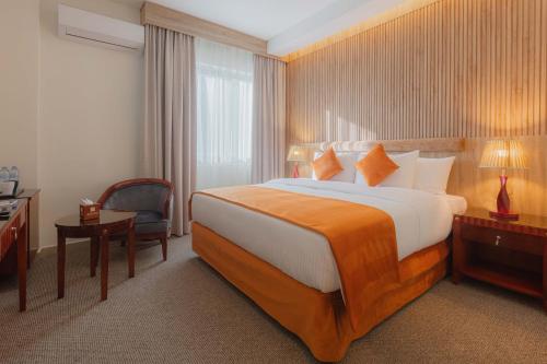 een hotelkamer met een groot bed en een stoel bij Amman Inn Boutique Hotel in Amman