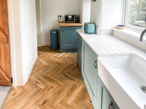 uma cozinha com lavatório e piso em madeira em Holme Cottage em Embsay