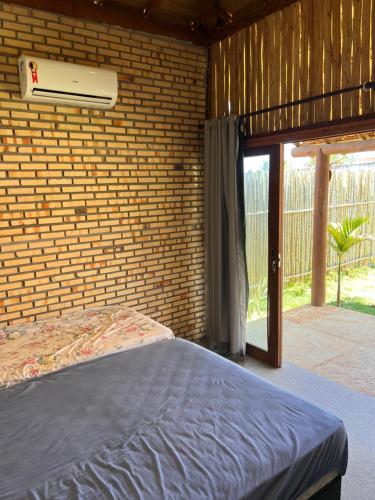 a bedroom with a bed and a brick wall at Bungalows Morro Do Chapeu Taiba in Taíba