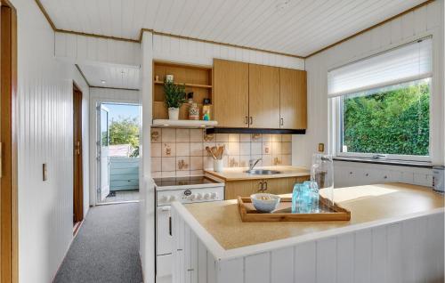 2 Bedroom Cozy Home In Kerteminde في كيرتيمايند: مطبخ بدولاب بيضاء ومغسلة ونافذة