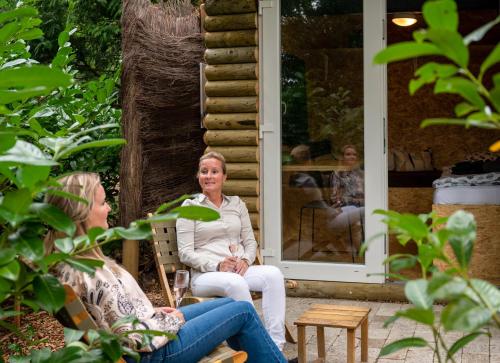 two women sitting on the porch of a house at ZEN-Bungalow NO 4 met sauna en hottub in Rheezerveen