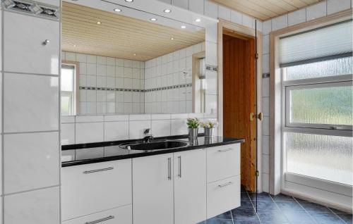 biała kuchnia ze zlewem i lustrem w obiekcie Nice Home In Hovborg With Sauna w mieście Hovborg