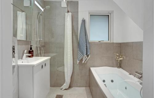 Baño blanco con bañera y lavamanos en Amazing Apartment In Blokhus With Wifi, en Blokhus