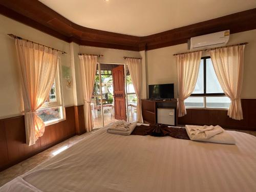 a bedroom with a large bed with windows and a television at Lanta Palm Beach Resort , Beach Front Bungalow - Koh Lanta in Ko Lanta