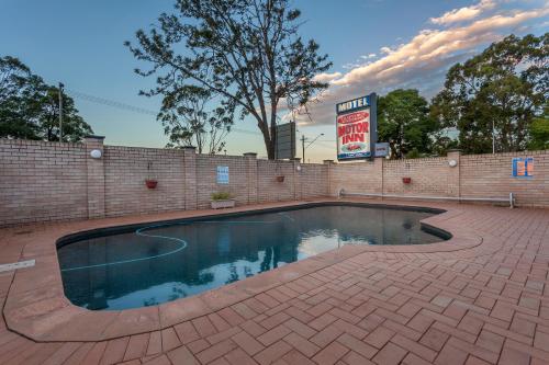 a swimming pool with a brick wall and a sign at Clifford Gardens Motor Inn in Toowoomba