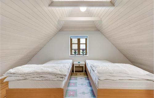 two beds in a attic bedroom with a window at 2 Bedroom Stunning Apartment In Aabenraa in Aabenraa