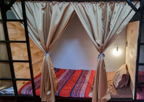 a bed in a room with a curtain at Rainbow House Ha Giang in Ha Giang