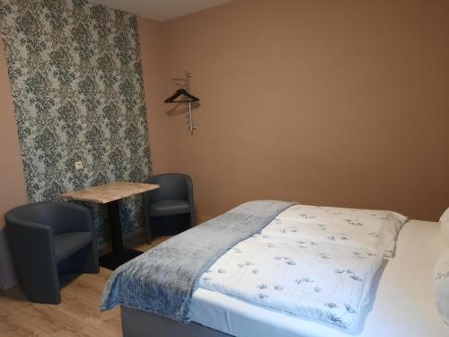 een slaapkamer met een bed en een tafel en stoelen bij Hotel Wittenberg-Hotel Garni in Lutherstadt Wittenberg