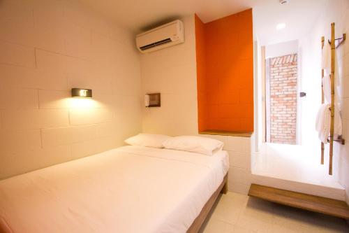 a small bedroom with a white bed and a window at Lantern Hotel in Kuala Lumpur