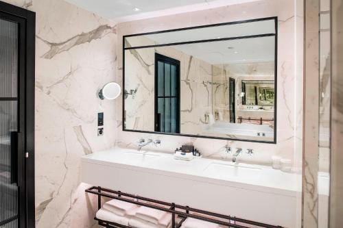 a bathroom with a sink and a large mirror at The Dixon, Tower Bridge, Autograph Collection in London