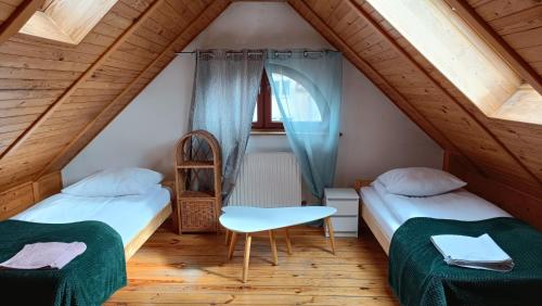 a room with two beds and a chair in a attic at DOM WYPOCZYNKOWY RYBNICKA - Apartamenty in Gdynia