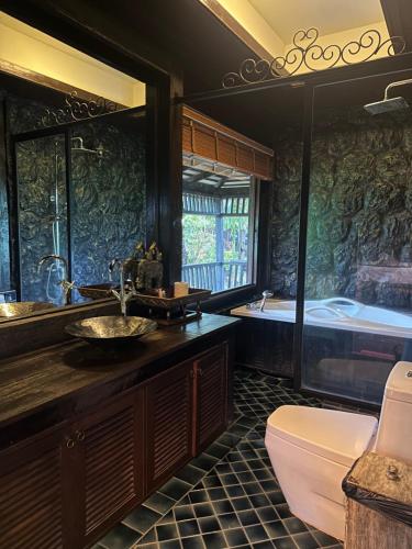 a bathroom with a tub and a sink and a toilet at Bantunglom Resort in Mae Rim