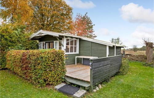 a small green house with a wooden deck at Cozy Home In Nexø With Wifi in Neksø