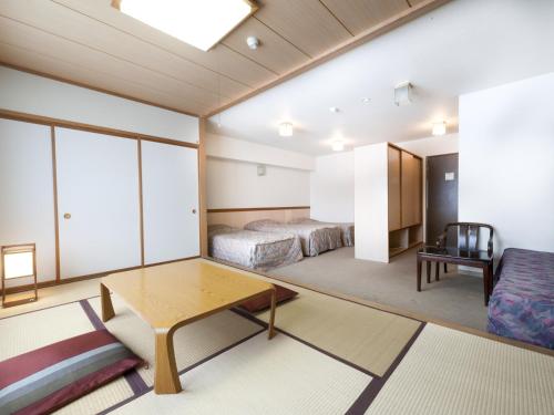 a room with two beds and a table and a couch at Kumanoyu Hotel in Yamanouchi