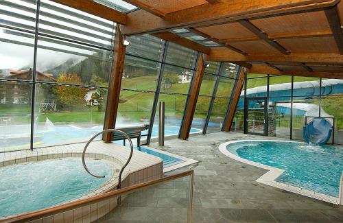 a large swimming pool in a building with windows at Apartment Cesa Collina Superior in Ortisei