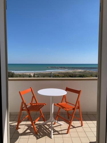 a table and two chairs on a balcony with the beach at La Bussola in Porto Palo