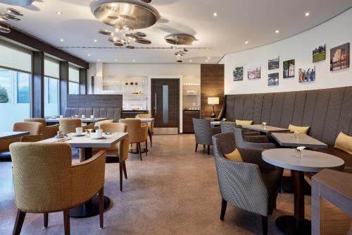 a dining room with tables and chairs in a restaurant at Sheraton Duesseldorf Airport Hotel in Düsseldorf