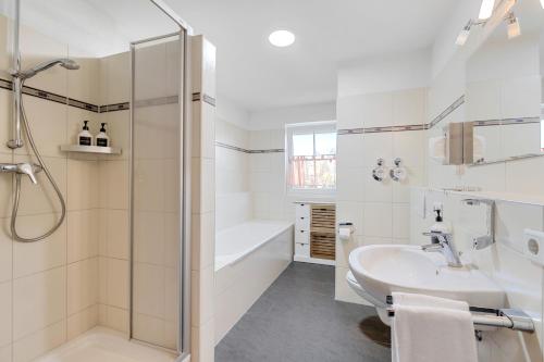 ein weißes Bad mit einer Dusche und einem Waschbecken in der Unterkunft Apartments Münchbach - near Europa-Park and Rulantica - Terrace I Parking I Kitchen I WiFi in Rust