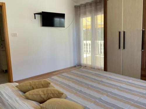 a bedroom with a bed with a flat screen tv on the wall at Apartman Tratica Ugljan in Ugljan