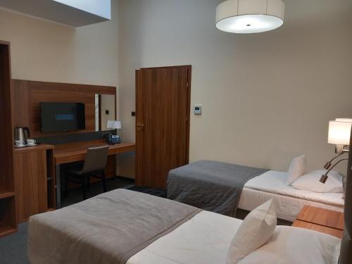 a hotel room with two beds and a desk at Hotel Wodnik in Bydgoszcz