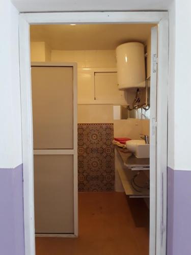 Une porte ouverte s'ouvre sur une cuisine équipée d'un évier. dans l'établissement Maison d'Hôte à Saïdia, à Saïdia
