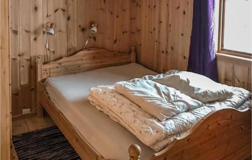 a bed in a room with a wooden wall at Nice Home In Straumgjerde With Kitchen in Brunstad
