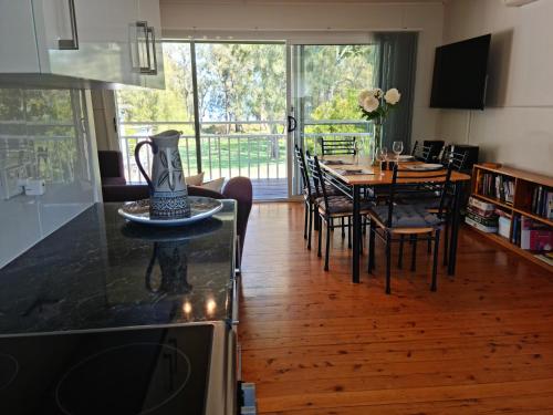 a kitchen and dining room with a table and chairs at Paradise Bungalow Waterfront in Sanctuary Point