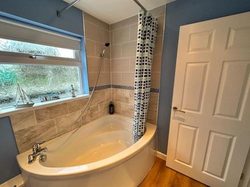 a large bathroom with a tub and a window at 1 Coach House - 3 bed period cottage built in 1686 in Tredegar