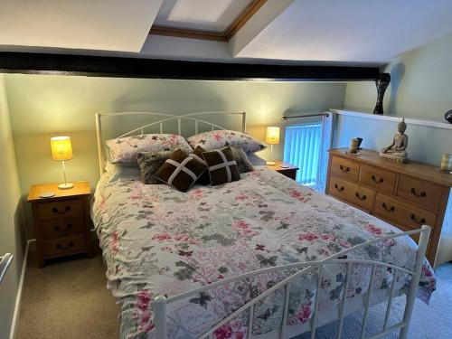 a bedroom with a bed with a floral bedspread at 1 Coach House - 3 bed period cottage built in 1686 in Tredegar