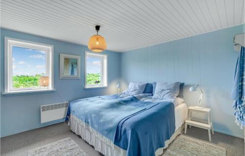 ein blaues Schlafzimmer mit einem Bett und zwei Fenstern in der Unterkunft Amazing Home In Lemvig With House Sea View in Lemvig