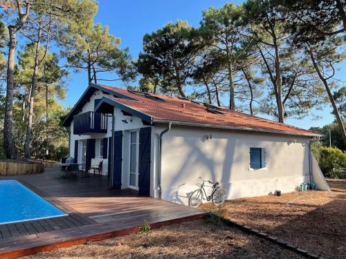 Cette petite maison blanche dispose d'une terrasse et d'une piscine. dans l'établissement Villa Mamychou, à Lacanau