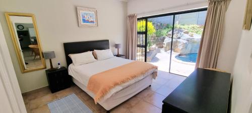a bedroom with a bed and a sliding glass door at Guinea Fowl poolside apartment in Cape Town