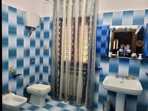 Baño de azulejos azules con aseo y lavamanos en Immaculate 4-Bed House in Cassino Villa Aurora, en Cassino