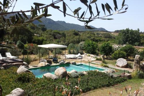 basen w ogrodzie ze skałami i parasolem w obiekcie Villa con piscina tra Porto vecchio e Bonifacio w mieście Figari