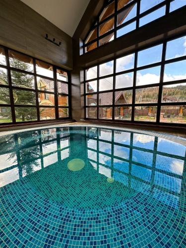 a large swimming pool in a building with windows at Hostynnyy Dvir Apartament Hotel & SPA in Slavske