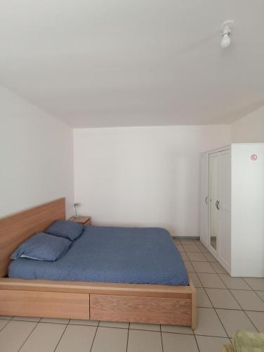 - une chambre avec un lit doté de draps bleus et une armoire dans l'établissement Joli studio spacieux au rez de chaussée, à Denain