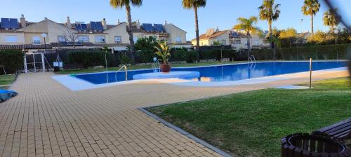 a swimming pool in a yard with palm trees and houses at CASA EN CAMPO DE GOLF CERCA DE LA PLAYA in Jerez de la Frontera