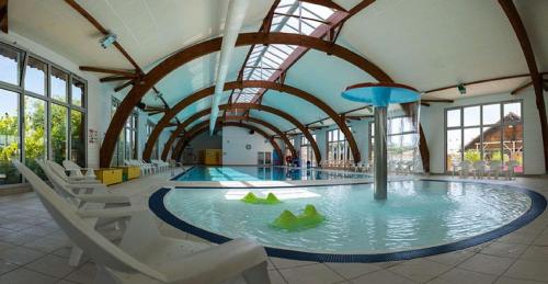 a large swimming pool with chairs in a building at mobil home 3chambres tout confort in Gastes