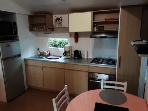 a small kitchen with a table and a sink and a stove at mobil home 3chambres tout confort in Gastes