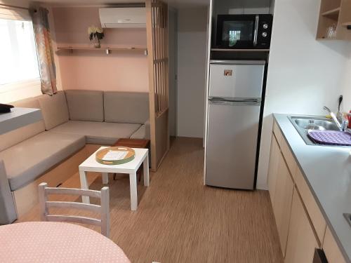 a small kitchen with a couch and a refrigerator at mobil home 3chambres tout confort in Gastes