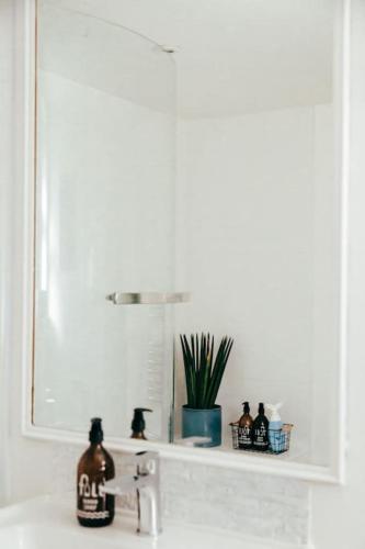 a bathroom sink with a mirror and a bottle on it at The Hideout - Newquay - Fully Stocked Eco Escape in Newquay